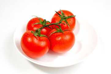 branch of red tomatoes on a white plate