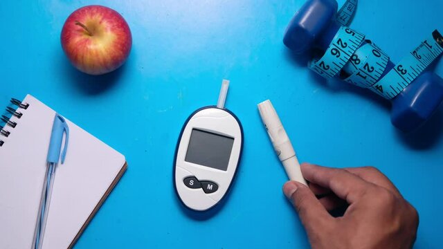  blood glucose meters, notepad and apple on blue desk 