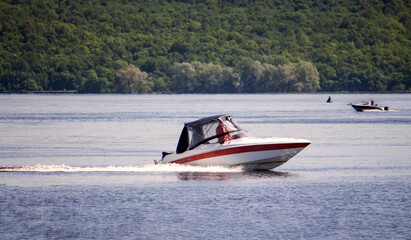 Fototapeta premium two small boats with motors are floating on a wide river