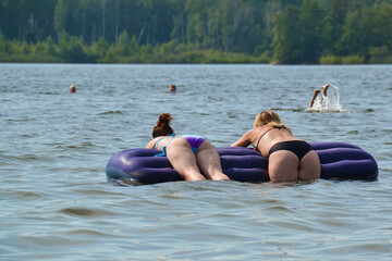 yong girls sunbathe on an air mattress on the lake