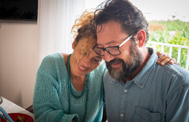 Attractive couple of man with beard and woman with blond and curly hair enjoying lunch at home - happy family concept