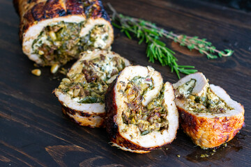 Mediterranean Stuffed Pork Tenderloin: Roasted pork stuffed with spinach, pesto, and goat cheese on a dark wood background