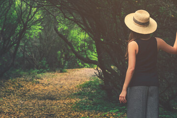 Woman wearing straw hat lost in the woods, looking for the exit