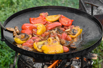 Fresh vegetables are cooked in a grill pan on open fire