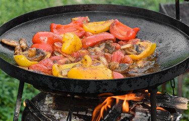 Fresh vegetables are cooked in a grill pan on open fire