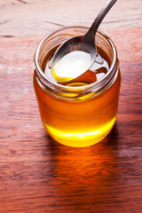 Glass jar with ghee and spoon with gold butter . Rustic still life over wooden background.