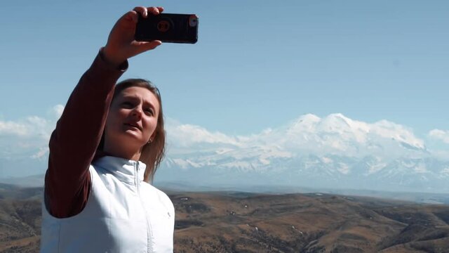 girl blogger is broadcasting on the phone in the background of a sleeping volcano