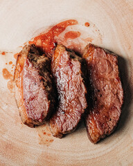Overhead shot of juicy and tender medium rare stake served on a wooden playe. The juices of the stake flow and show how delicious it is.