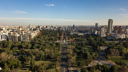 Fototapeta na wymiar Aerial view on the empty big avenue (due to coronavirus quarantine) in between of the public parks and gardens with the statue in the middle of the roundabout, Palermo, Public Parks, Buenos Aires
