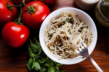 Nutrition concept - Healthy food, Diet, Detox, Clean Eating or Vegetarian concept. Healthy pasta with sauce, basil, fresh tomatoes over rustic wooden background