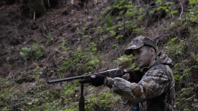 Man hunter takes aim with rifle. Men take aim. Man in comfortable camouflage clothes hunter outdoor in forest hunting alone.