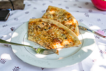 Pieces of pizza on a plate on a table with tablecloth and cutlery, Germany
