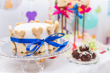 
A festive banquet for a dog’s birthday, a cake with bone decorations, meatballs and burgers on skewers.