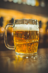 Glass glass of light beer. Glass of light beer with wheat at the bar counter. Mug of beer on a wooden background.