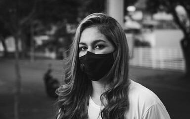 Photograph of young woman with face mask sitting in a park