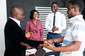 Dark-skinned people are in the office and shake hands and smile. Beneficial business cooperation.