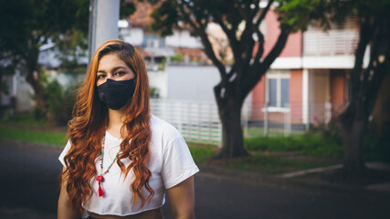 Fototapeta premium Photograph of young woman with face mask sitting in a park
