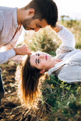 Portrait of a beautiful couple lying on the grass. Gently touch in the face, hug and kiss the girl. Hold hands