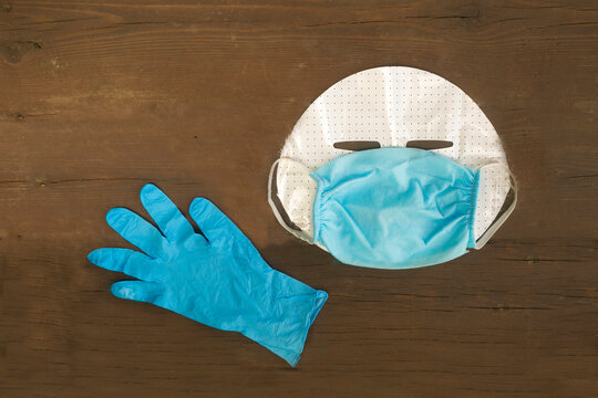 masked human face with glove on wooden background