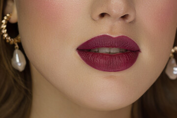 Cosmetics, makeup and trends. Bright lip gloss and lipstick on lips. Closeup of beautiful female...