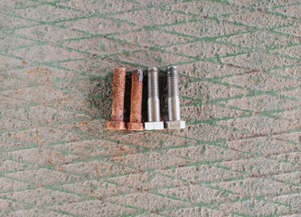 Rusty and new bolts lie on a metal background for comparison. Metal details, accessories at an...