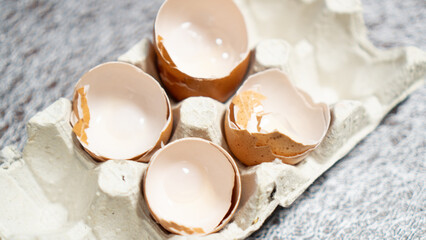 broken eggshell in paper tray. Many broken eggshell on cardboard box. used brown eggshell. shell recycling concept
