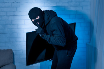 Thief breaking in an apartment and stealing tv
