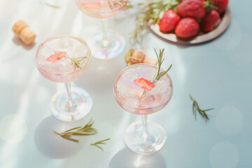Glass of strawberry cocktail or mocktail, refreshing summer drink with crushed ice and sparkling water on light blue background.