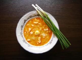 Potato soup with green onion on the brown table.