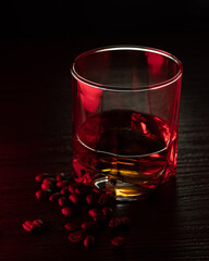 Cognac glass in ruby light with white, amber highlights, grains near the glass.