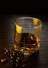 A glass of cognac. A glass of cognac in gold-amber light with grains of coffee near the glass.