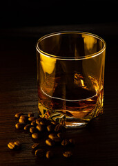 A glass of cognac. A glass of cognac in gold-amber light with grains of coffee near the glass.