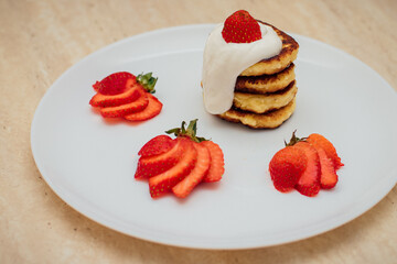 Delicious homemade pancakes with strawberries on plate on a light background
