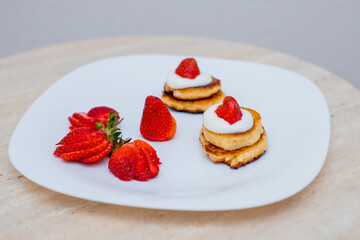 Delicious homemade pancakes with strawberries on plate on a light background