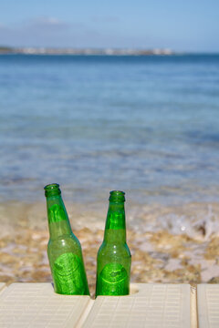 Vertical photo of two green bottles of beer facing the sea