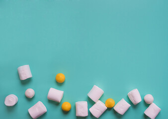 White marshmelows on a turquoise background. Stylish advertising wallpaper with candy and marshmallows. Round yellow gum
