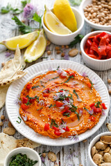 Roasted pepper hummus sprinkled with chopped parsley and edible chive flowers, top view