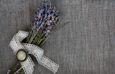 Dry lavender flowers bouquet on rustic linen fabric background.