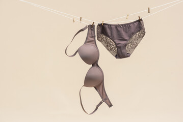 Female bra and panties is hanging on the rope isolated on a light background. - obrazy, fototapety, plakaty