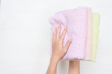 Heap of bath towels in female hand on white background.