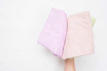 Heap of bath towels in female hand on white background.