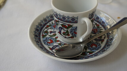 Small turkish style coffee cup with a teaspoon on a white table. Eastern cuisine.