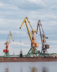 Fototapeta na wymiar Shipbuilding plant. Crane operation at the shipbuilding, commercial, sea, river, port. Loading, unloading of goods, bulk materials by cranes of the river port (dock).
