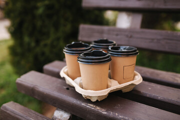 Four cup with coffe on bench outdoors. Take-out concept