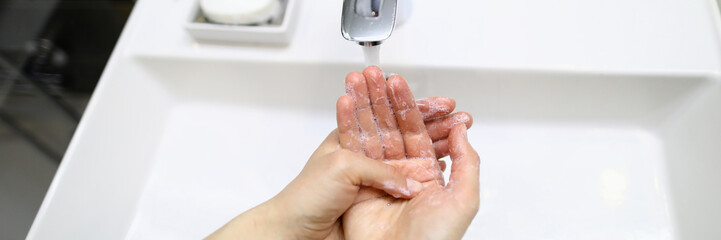 Female wet hands soaped in bathroom over sink closeup background. Wash hands before eating concept