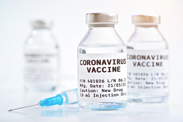 Coronavirus Covid-19 vaccine concept - glass vials with metal caps on white table, blurred...