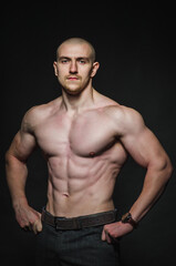 Fototapeta premium Sporty sexy man stands Topless on a dark background. Sports, beauty