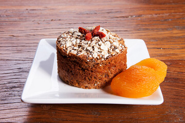 Traditional homemade Christmas cake. Holiday dessert with Damascus and dry goji berry on vintage wooden table background. Rustic style.