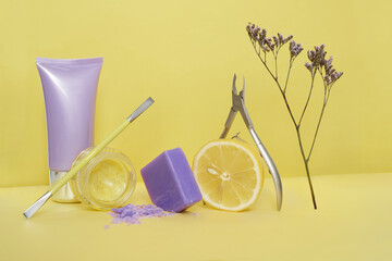 Manicure or pedicure tools pusher, nail clippers, cosmetic tube, jar with yellow cream, soap, lemon...