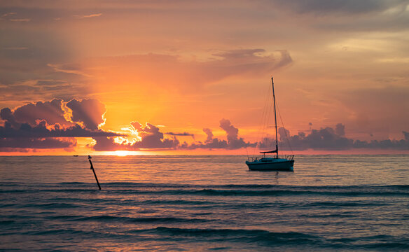 Sailing boat moored close to the beach with the sunset as background
